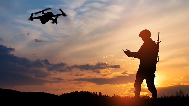 Silhouette of soldier are using drone and laptop computer for scouting during military operation against the backdrop of a sunset. Greeting card for Veterans Day, Memorial Day, Independence Day.