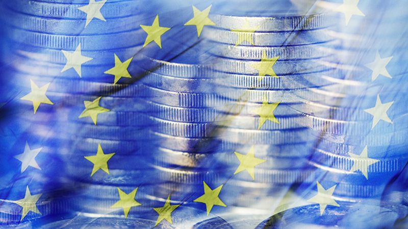 a multiple exposure of some piles of euro coins and a flag of the European Union