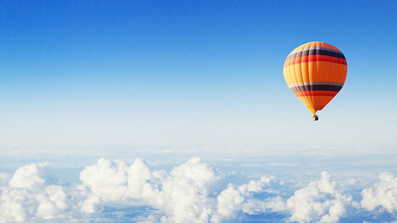 inspiration or travel background, fly above the clouds, colorful hot air balloon in blue sky