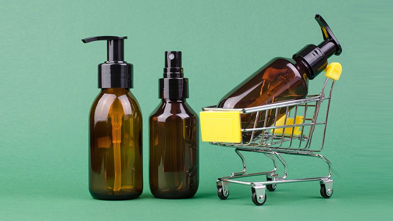 Brown cosmetic bottles on a green background, selective focus. The concept of online shopping for cosmetic products